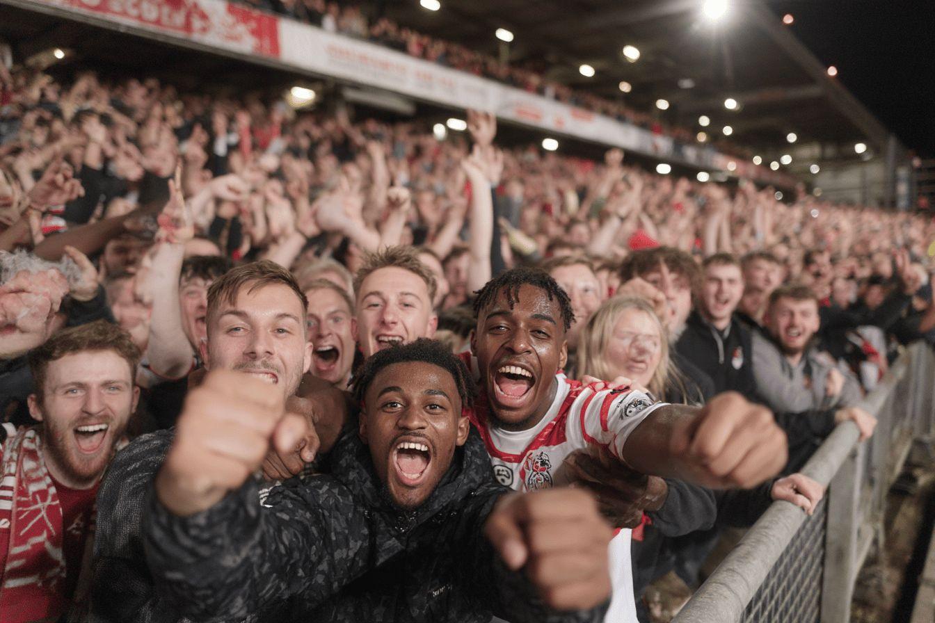 Excited crowd cheering at sports event with raised fists